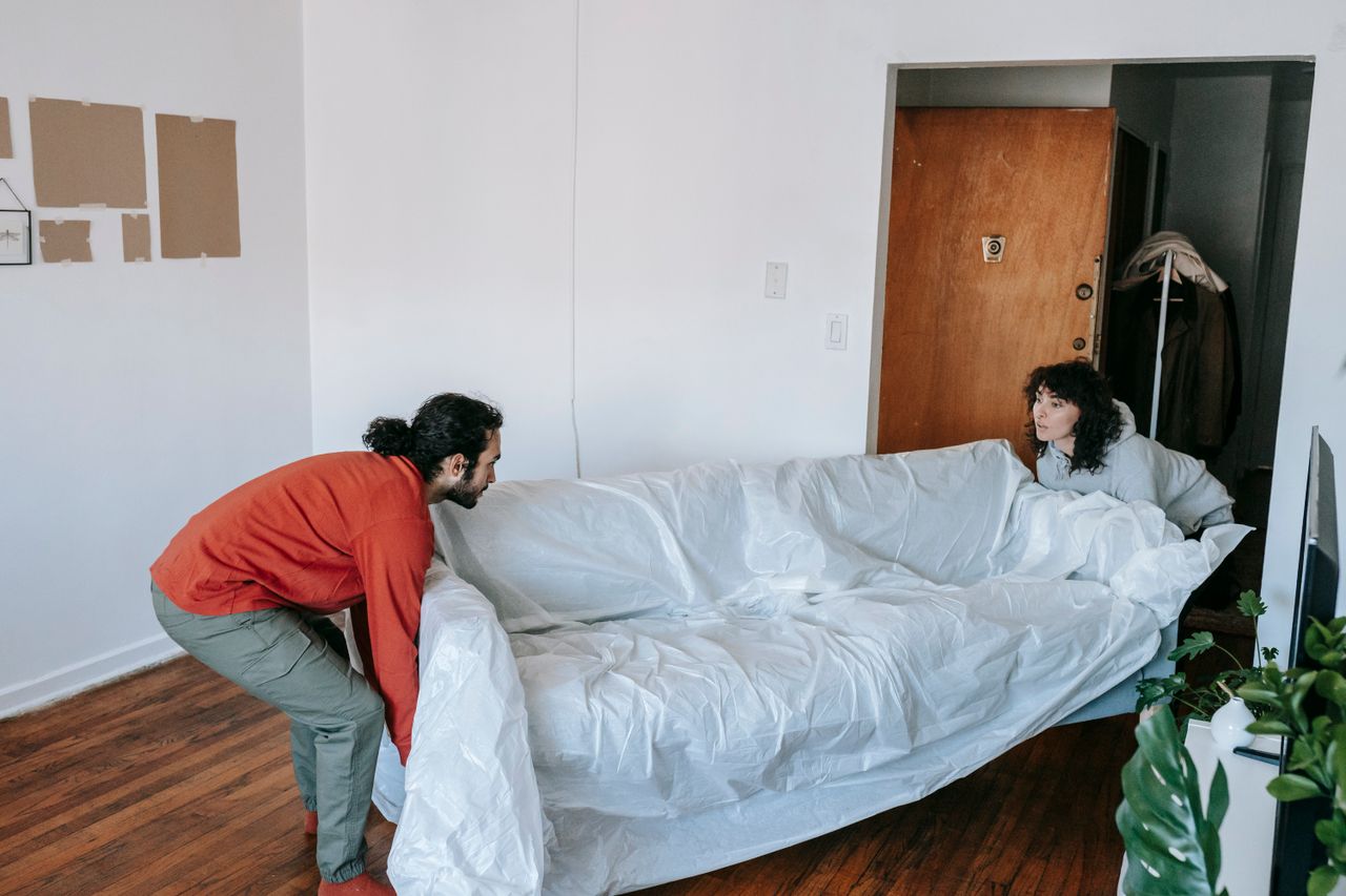 Un couple travaillant ensemble pour soulever un canapé lors de son emménagement dans un nouvel appartement.